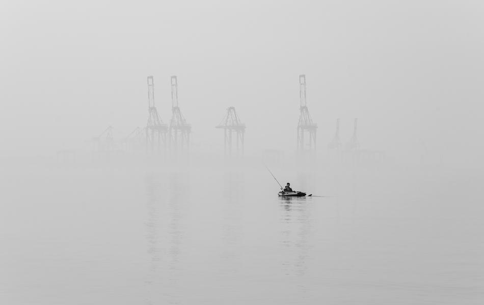 Silhouettes of port cranes in the fog